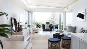 A modern living room with a sofa, chairs, a coffee table, and a dining area. - The Waterview, 2 76 Magnus St -  complete style, comfort, luxury and spectacular waterviews (Nelson Bay)