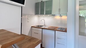 Una cocina compacta con armarios blancos, lavavajillas integrado y encimera de madera.