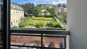 Vista desde una ventana sobre un jardín cuidado, con setos podados y diversas especies de árboles.