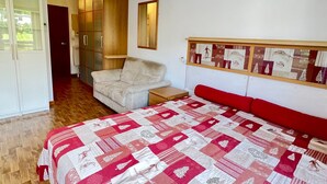 Un dormitorio con cama, una silla, un armario y un espejo.