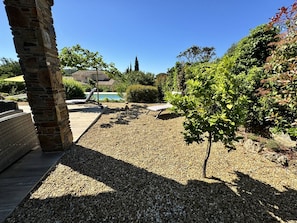 Un patio con piscina, rodeado de grava y follaje.