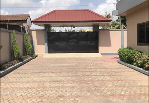 residence with a modern design, featuring a gated entrance and well-manicured landscaping.