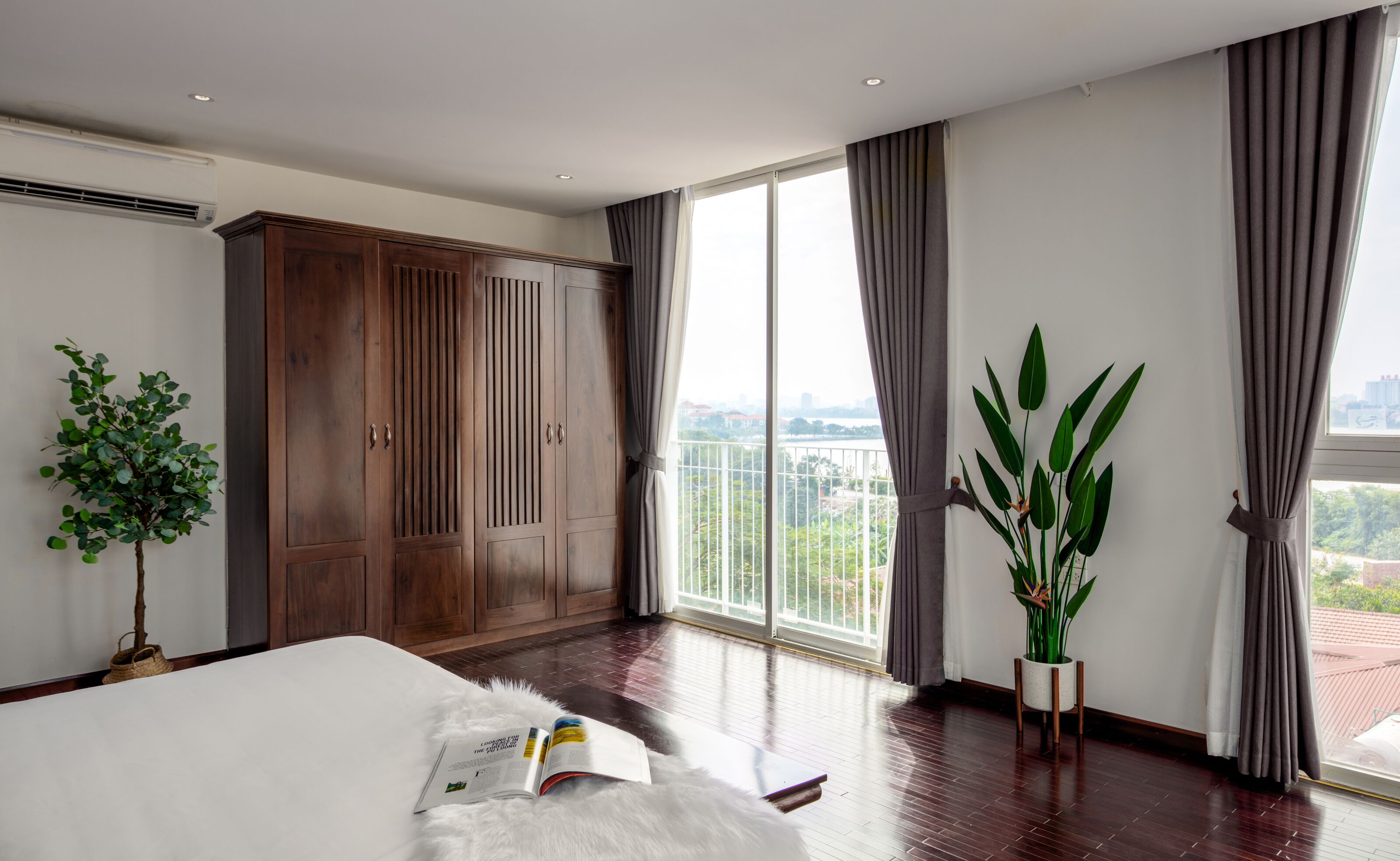 Ein geräumiges Schlafzimmer mit einem großen Bett, einem Kleiderschrank und einem Balkon mit Blick auf die Stadt.
