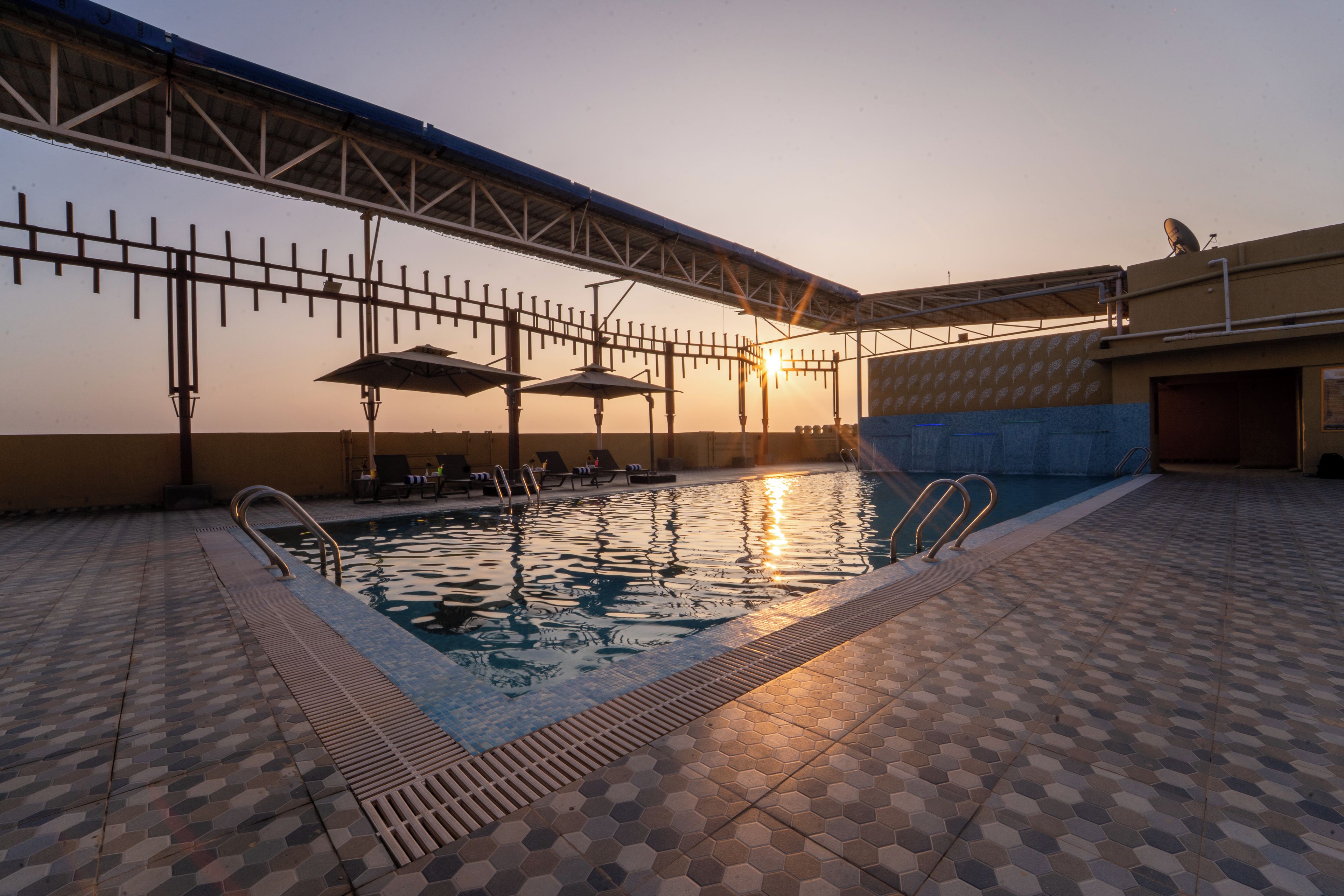 Una piscina al aire libre con solárium empinado, tumbonas y sombrillas.