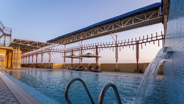 Ein Schwimmbad mit Brücke, Liegestühlen und einem Wasserspiel.