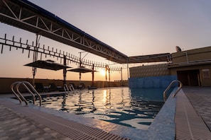 A swimming pool with sunbathing areas and a covered walkway. - The Royal Bihar (Danapur)
