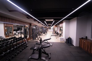 A gym with various exercise equipment, including dumbbells and weight machines, and a mirrored wall. - The Royal Bihar (Danapur)