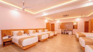 A hotel room with four beds, a small kitchenette, and a ceiling fan. - The Royal Bihar (Danapur)