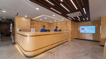 A reception desk with two employees, a digital display with a message, and a modern interior design.