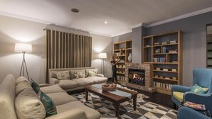 A living room with a sofa, a coffee table, a fireplace, and bookshelves.