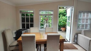 A dining area with a wooden table and four chairs, a sofa, and a radiator.