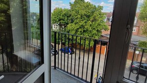 A balcony with a view of a tree and parked cars.