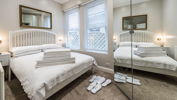 A hotel room with two beds, a large mirror, and a view of the outside through the window.