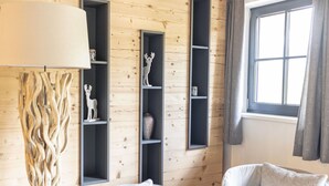 Un soggiorno moderno con pareti in legno, una lampada da terra grande, due poltrone bianche e scaffali a muro.