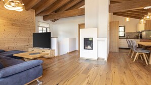 Un soggiorno moderno con soffitto in legno, camino, zona pranzo e cucina.