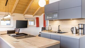 Una cucina moderna con soffitto in legno, mobili grigi, forno a microonde integrato e macchina da caffè in acciaio inossidabile.