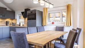 A modern kitchen with a central island, a dining table with chairs, and a window with curtains. - Lovely apartment for 8 people with WIFI, TV and terrace (Brandstätter)