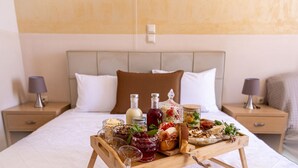 A neatly arranged breakfast tray on a bed with a headboard, two bedside tables with lamps, and a plain wall in the background. - Buka Sandy Beach  (Messini)