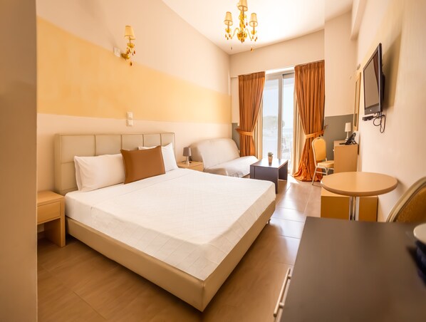 Habitación de hotel con una cama grande, un escritorio, una silla, un televisor y una ventana con cortinas.