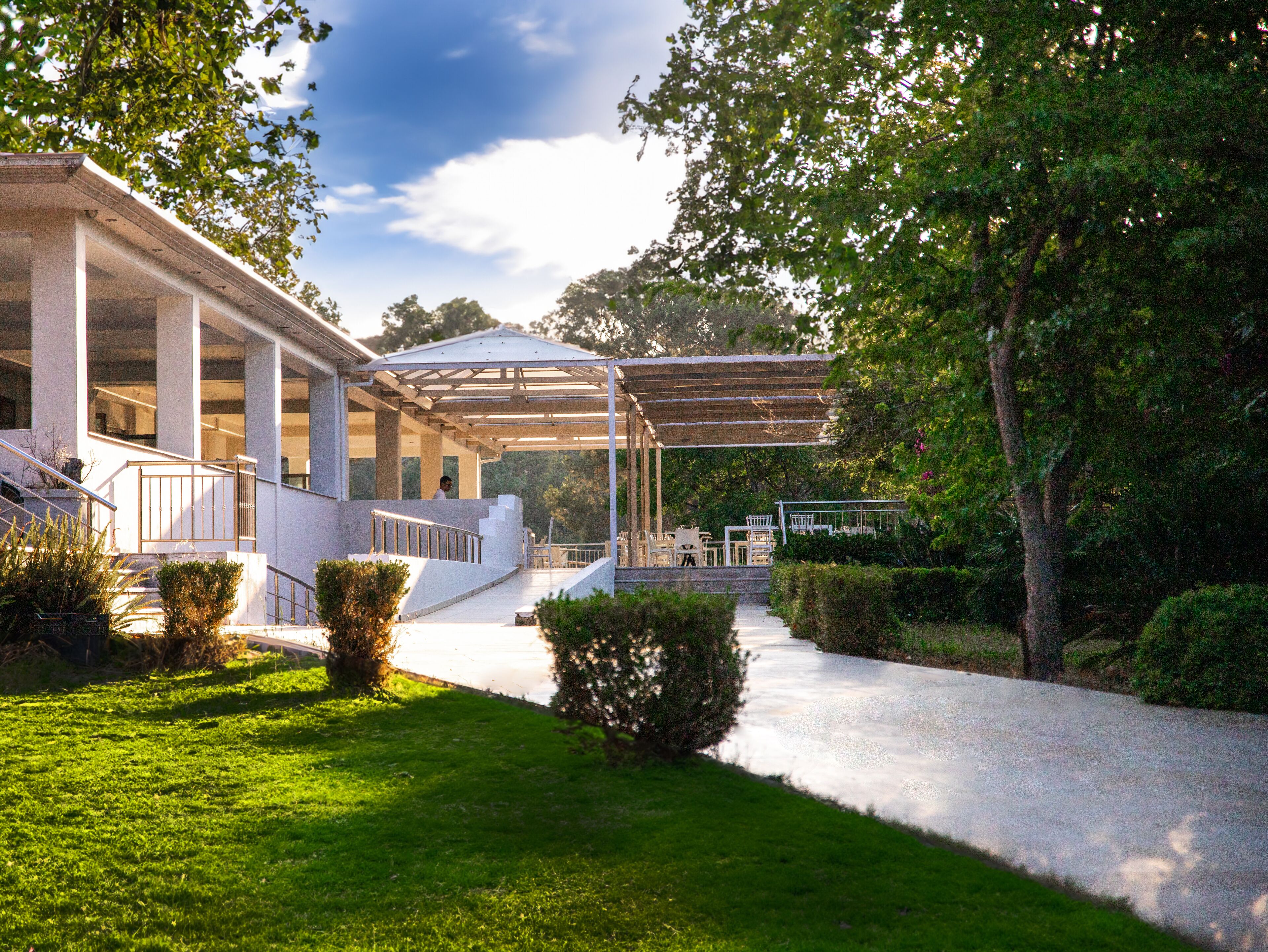 A covered outdoor area with steps leading to a building, surrounded by greenery.