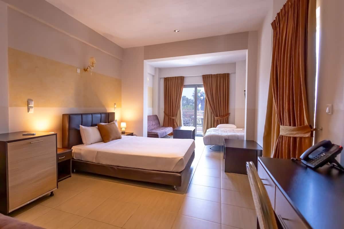 A hotel room with a bed, bedside tables, a desk, and a phone.