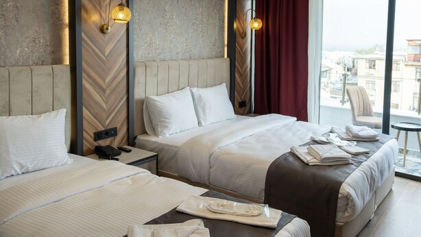 Quarto de hotel com duas camas, uma janela ampla com vista para a cidade e decoração moderna.