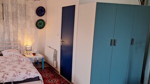 A bedroom with a bed, bedside tables, a nightstand, a dresser, and a radiator.