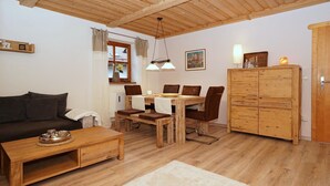 A cozy living room with a wooden dining table, brown leather chairs, a sofa, and a cabinet.