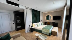 Una habitación de hotel moderna con cama, escritorio, televisor y sofá.