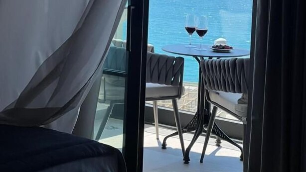 Un balcón con una mesa dispuesta para dos personas, con vista a una masa de agua.