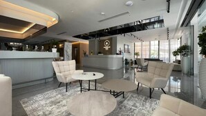 Un moderno vestíbulo de hotel con un mostrador de recepción, área de descanso y una escalera.
