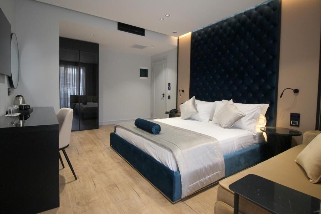 A modern hotel room with a large bed, a desk, and a seating area.