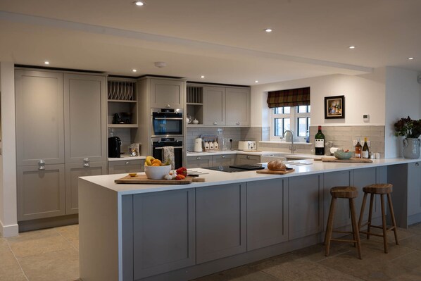 A modern kitchen with grey cabinetry, a central island, and a built-in oven. - Luxury hunting lodge with hot tub on stunning Scottish estate (Perth)