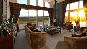 Un salón amplio con chimenea, ventanas grandes y vistas al campo.