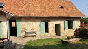 A stone building with a tiled roof, green shutters, and a bench outside. - Charmante Maison Périgourdine (Granges-d'Ans)