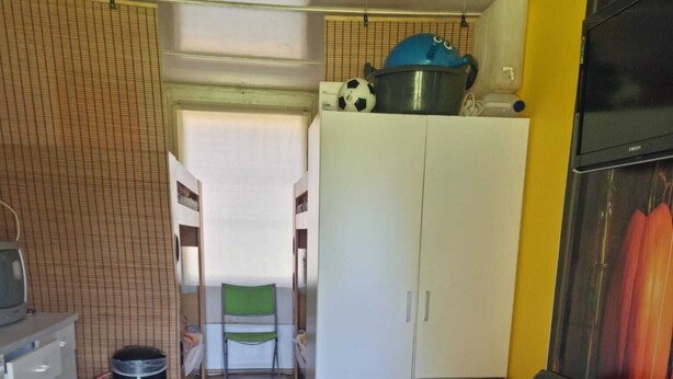 Ein kompakter Wohnraum mit Küchenzeile, einer Couch mit Kissen und einem Essbereich.