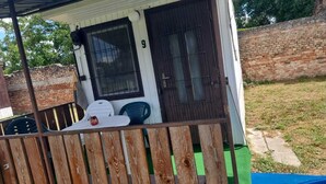 Ein kleines Haus mit einer Veranda, der Hausnummer 9 an der Tür und einer Ziegelwand im Hintergrund.