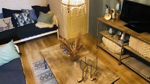 Una sala de estar acogedora con un sofá, una mesa de centro, un mueble para la televisión y una lámpara decorativa.