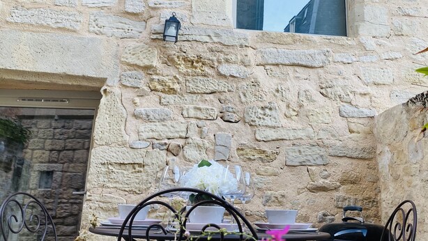 Un edificio de piedra con una ventana y una mesa con sillas al frente.