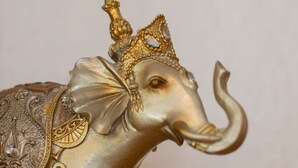 Una estatua dorada de elefante con diseños intrincados y una corona.