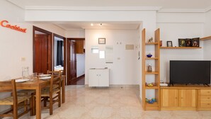 Una sala de estar con comedor, televisor y estantería.