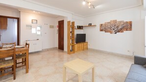 Una sala de estar con un mueble de televisión de madera, una mesita y un sofá gris.