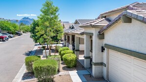 A row of single-story homes with attached garages, neatly arranged along a street with a clear view of mountains in the background. - Modern, 3 Bedroom Home Near Superstition Mountain! (Apache Junction)