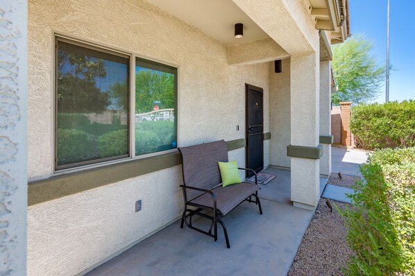 A building exterior with a textured facade, a door, and a bench with a cushion. - Modern, 3 Bedroom Home Near Superstition Mountain! (Apache Junction)