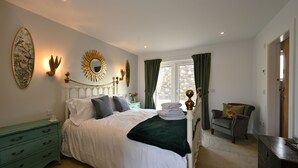 A bedroom with a bed, nightstands, a dresser, and a window with curtains. - Luxury two bedroom converted steading (Perth)