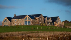 A large stone house with multiple large windows and a sloped roof. - Luxury two bedroom converted steading (Perth)