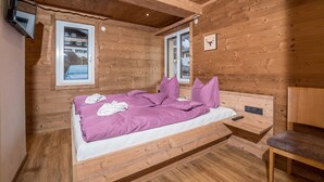 A wooden cabin bedroom with a bed, a nightstand, and a chair. - 1213 Vallüla Schima Drosa (Gaschurn)