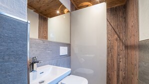 A modern bathroom with a white sink, a toilet, and a wooden wall. - 1213 Vallüla Schima Drosa (Gaschurn)
