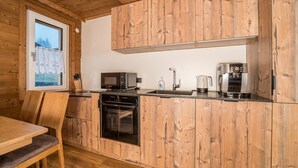 A kitchen with wooden cabinetry, a microwave, a coffee maker, and a dishwasher. - 1214 Piz Buin Schima Drosa (Gaschurn)