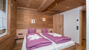 A room with two beds, wooden walls, and a window with lace curtains. - 1214 Piz Buin Schima Drosa (Gaschurn)